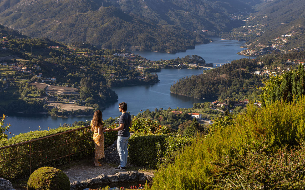 Explore Pousadas de Portugal overlooking visitors admiring a river valley framed by forested mountains